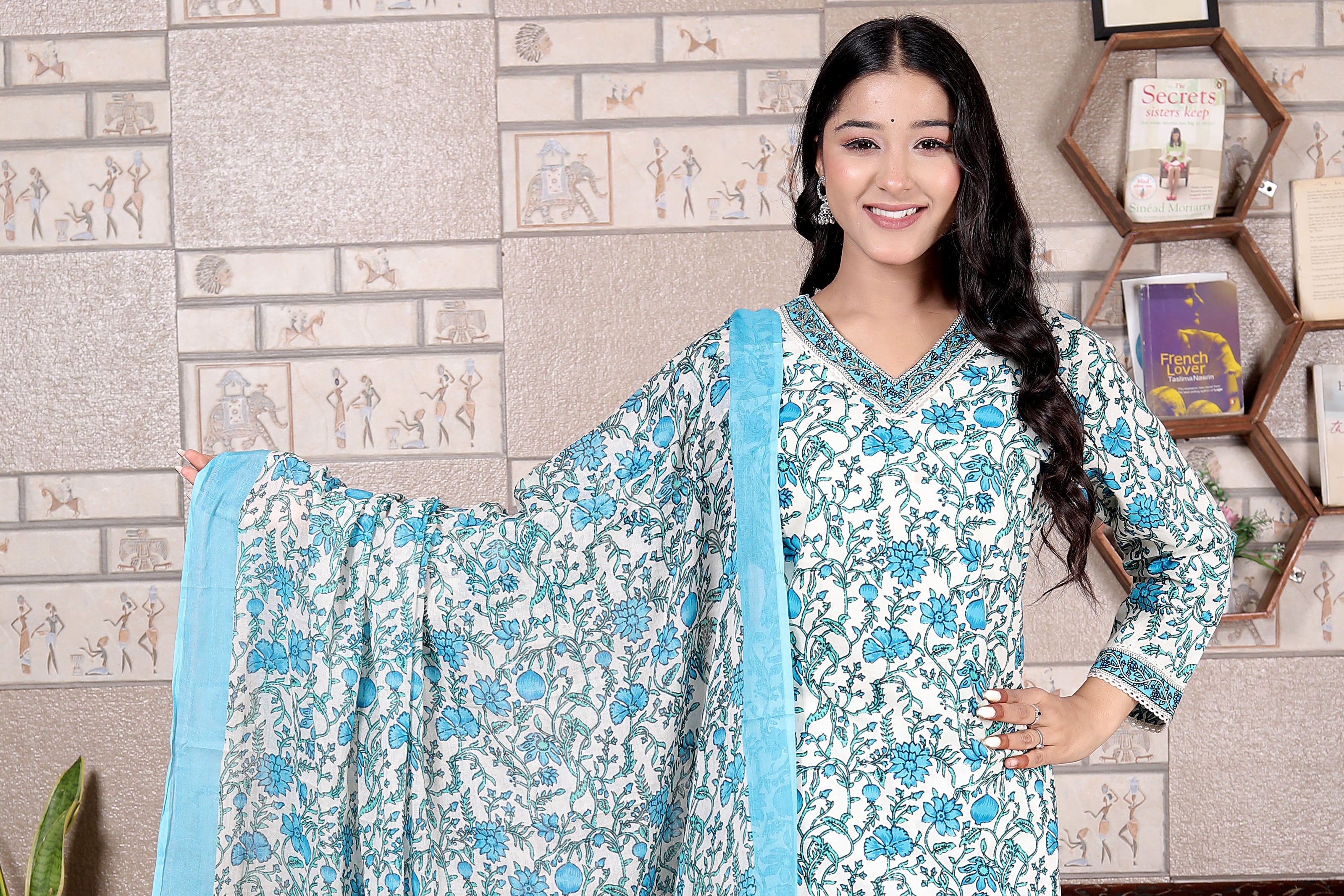 Woman wearing a blue and white floral dress with a matching dupatta in a room setting.
